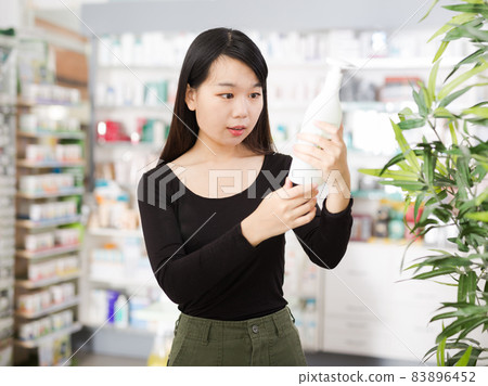 Positive chinese woman near counter chooses antibacterial at in pharmacy 83896452