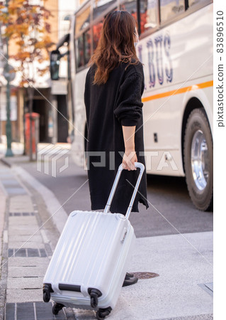 一個女人拿著手提箱,孤獨地等待公共汽車 一個女人拿著手提箱,孤獨地等待公共汽車 83896510