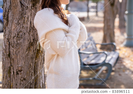 A woman wearing a white fluffy knit and waiting for her boyfriend 83896511