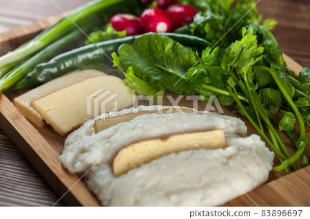 Mengrelian corn mamalica (ghomi) with cheese and various herb on wooden table. Georgian traditional food Mengrelian corn mamalica (ghomi) with cheese and various herb on wooden table. Georgian traditional food 83896697