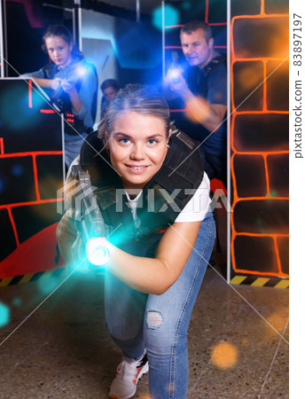 joyous girl with laser pistol playing laser tag with friends 83897197