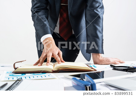 Businessman analyzing financial documents at desk 83899531
