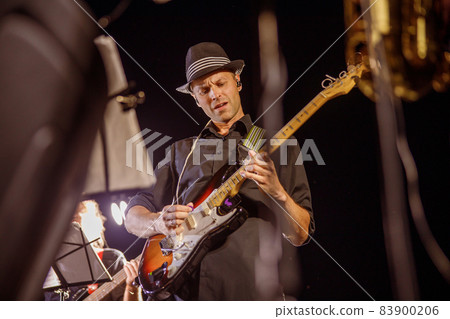Handsome man playing guitar at night outdoor concert 83900206