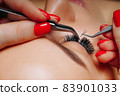 Eyelash Extension Procedure. Woman Eye with Long Eyelashes. Close up, selective focus. 83901033