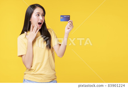 Cheerful young woman wearing casual clothes while holding credit card mockup in own hand Cheerful young woman wearing casual clothes while holding credit card mockup in own hand 83901224