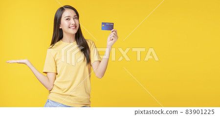Cheerful young woman wearing casual clothes while holding credit card mockup in own hand Cheerful young woman wearing casual clothes while holding credit card mockup in own hand 83901225