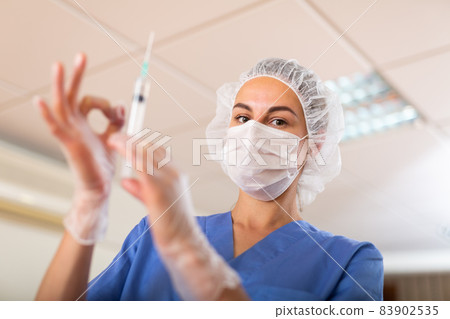 Nurse prepares a syringe for injection Nurse prepares a syringe for injection 83902535