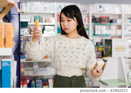 Young chinese woman chooses antibacterial at the pharmacy Young chinese woman chooses antibacterial at the pharmacy 83902672