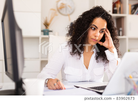 Portrait of worried young female manager working on laptop Portrait of worried young female manager working on laptop 83902673