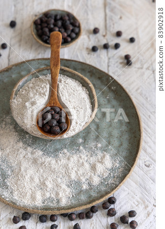 Plate of black chickpea flour and wooden spoon of beans closeup 83902918