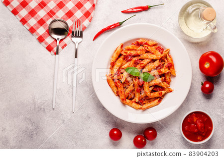 Classic italian pasta penne alla arrabiata with fresh basil on a light background 83904203