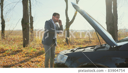 Desperate businessman standing and speak on phone near the broken car opened the hood road help repair stress problem emergency. 83904754