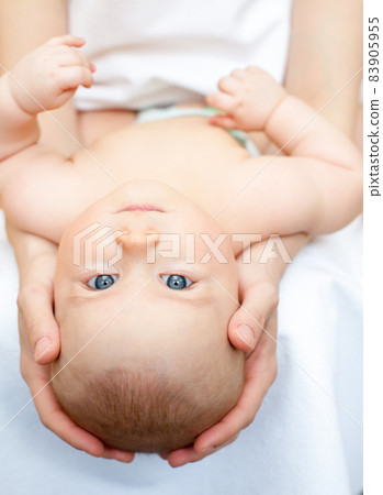 Baby girl looking out from green leaves Baby girl looking out from green leaves 83905955