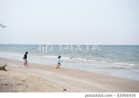 Seascape with fishing boat floating in the sea with blurred foreground of little boy and girl playing on the beach Seascape with fishing boat floating in the sea with blurred foreground of little boy and girl playing on the beach 83906936