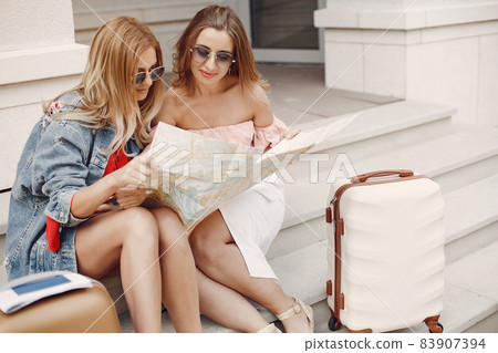 Elegant and stylish girl sitting with a suitcase Elegant and stylish girl sitting with a suitcase 83907394