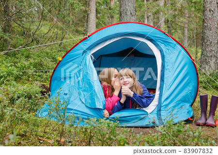 Girls sharing a secret in a tent during summer holidays Girls sharing a secret in a tent during summer holidays 83907832
