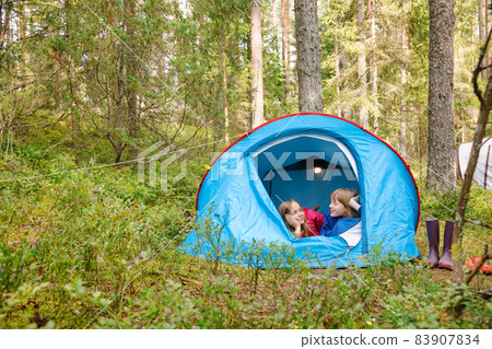 Girls chatting lying together in a tent enjoying summer holidays Girls chatting lying together in a tent enjoying summer holidays 83907834