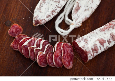 Slicing delicious Spanish smoked sausage fuete Slicing delicious Spanish smoked sausage fuete 83910372