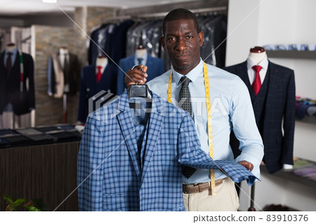 Male tailor demonstrating of fashionable suit in apparel shop Male tailor demonstrating of fashionable suit in apparel shop 83910376