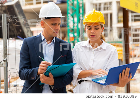 Two architects with laptop discussing construction plan Two architects with laptop discussing construction plan 83910389