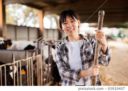 Portrait of active chinese female employee working in cowshed on farm 83910407