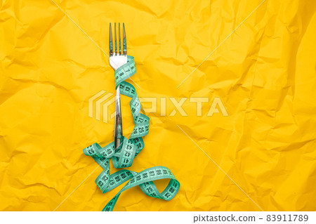 Iron fork with measuring tape with a space paper for text. Crush paper. Diet and healthy food concept. Healthy lifestyle. 83911789