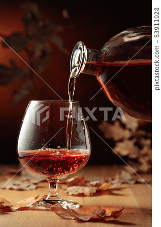 Cognac is poured into a glass from a bottle. 83911928