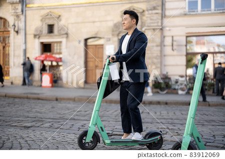 Asian businessman riding electric scooter in city 83912069
