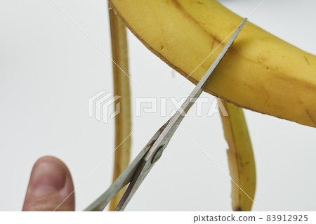 A person making banana peel fertilizer with banana cuts. A woman hand cutting banana skin into small pieces 83912925