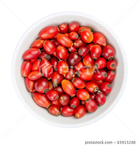 Fresh wild rose hips, in a white bowl. Also known as rose haw or rose hep. Ripe and intense red fruits, used for herbal teas, jam and can be eaten raw. One of the richest vitamin C sources in plants. 83913286