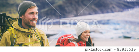 Two hikers people walking together hiking in wilderness. Alpine climbers mountaineering couple trekking in ice snow mountains. Panorama banner of team hiking in winter. 83913539