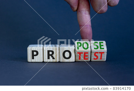 Propose instead protest symbol. Businessman turns wooden cubes, changes the word 'protest' to 'propose'. Beautiful grey table, grey background. Business, protest or propose concept. Copy space. 83914170