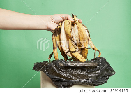 Woman throwing banana peels in trash can. Throw out banana peels in garbage. Banana skin in recycling bio bin in the kitchen Woman throwing banana peels in trash can. Throw out banana peels in garbage. Banana skin in recycling bio bin in the kitchen 83914185