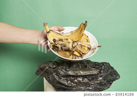 Woman throwing banana peels in trash can. Throw out banana peels in garbage. Banana skin in recycling bio bin in the kitchen 83914189