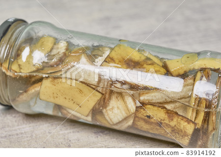 A jar filled with banana peel cuts and water. Banana peel for plant fertilization. Eco friendly natural way of fruit waste compost. Banana peel compost 83914192