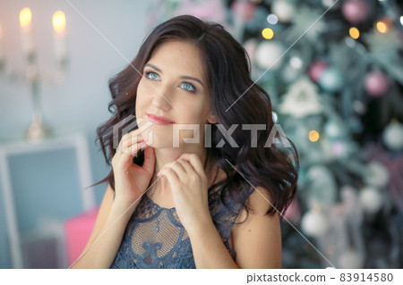 Beautiful portrait of a woman in a Christmas outfit on the background of a Christmas tree 83914580