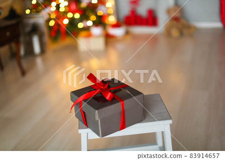 Christmas box with a gift tied with a ribbon on the background of a Christmas tree Christmas box with a gift tied with a ribbon on the background of a Christmas tree 83914657