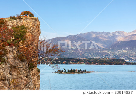 Rocky cliff of Lake Garda and a view of the little Rabbit island in autumn period Rocky cliff of Lake Garda and a view of the little Rabbit island in autumn period 83914827