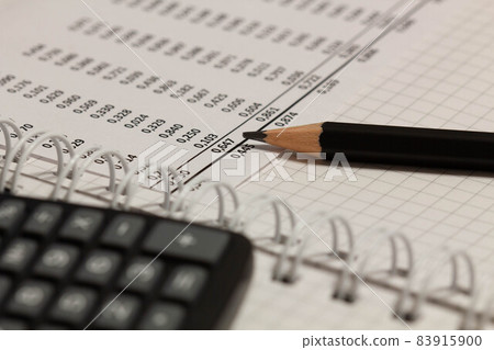 Financial report, pencil and paper with numbers on the table in the office. A paper sheet full of business data. Accounts number on the data paper. Business documents on office table. Close-up 83915900