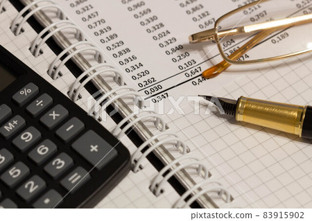 Financial report, a fountain pen, glasses and paper with numbers on the table in the office. A paper sheet full of business data. Accounts number on the data paper. Business documents. Close-up Financial report, a fountain pen, glasses and paper with numbers on the table in the office. A paper sheet full of business data. Accounts number on the data paper. Business documents. Close-up 83915902