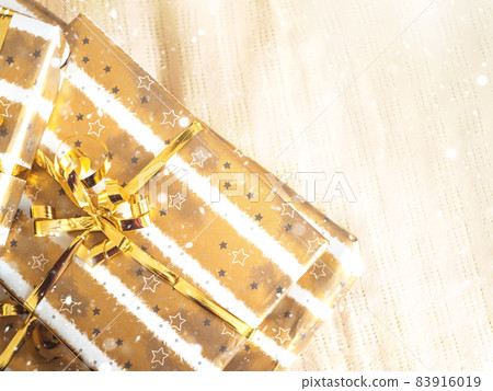 Christmas stack of golden wrapped gift boxes on beige plaid 83916019