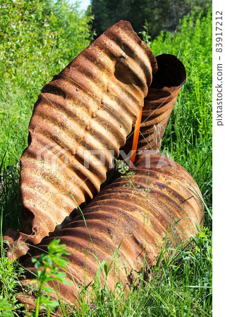A rusty twisted culvert in the grass A rusty twisted culvert in the grass 83917212