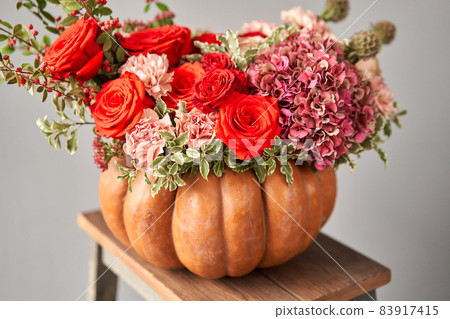 Flowers arrangement in pumpkin on wooden table. Fresh cut flowers for decoration home. European floral shop. Delivery fresh cut flower. Flowers arrangement in pumpkin on wooden table. Fresh cut flowers for decoration home. European floral shop. Delivery fresh cut flower. 83917415