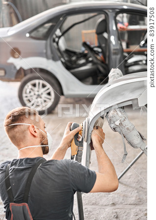 Sanding of car elements. The mechanic works with a grinding tool. Painting car service. Repairing car section after the accident. 83917508