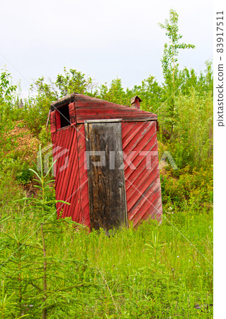 A red outhouse along a hiking trail 83917511