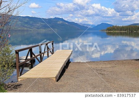 View of a lake with a dock and mountains in the background View of a lake with a dock and mountains in the background 83917537