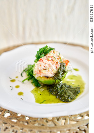 Crab salad tartare. Fresh Crab, avocado and pesto sauce with red caviar on a plate. Selective focus Crab salad tartare. Fresh Crab, avocado and pesto sauce with red caviar on a plate. Selective focus 83917612