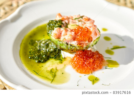 Raw salmon tartare. Fresh salmon, avocado and pesto sauce with red caviar on a plate. Selective focus Raw salmon tartare. Fresh salmon, avocado and pesto sauce with red caviar on a plate. Selective focus 83917616