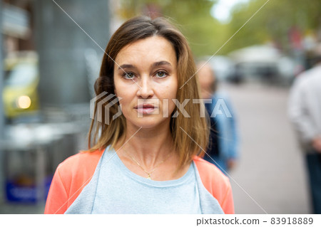 Portrait of brown-haired woman walking along city street Portrait of brown-haired woman walking along city street 83918889