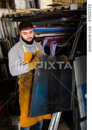 Skilled man worker working with metal sheet 83920259
